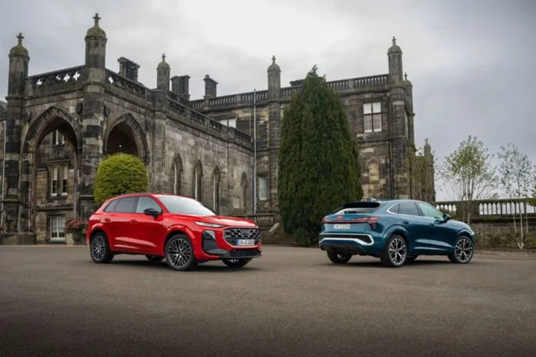 Vista leterla de dos modelos Audi Q3 Sportback 2026 en rojo y azul mostrando su silueta deportiva y diseño coupé, teniendo como fondo un castillo europeo
