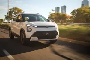 White Nissan SUV driving on a highway with trees and city skyscrapers in the background, motion blur suggests speed.