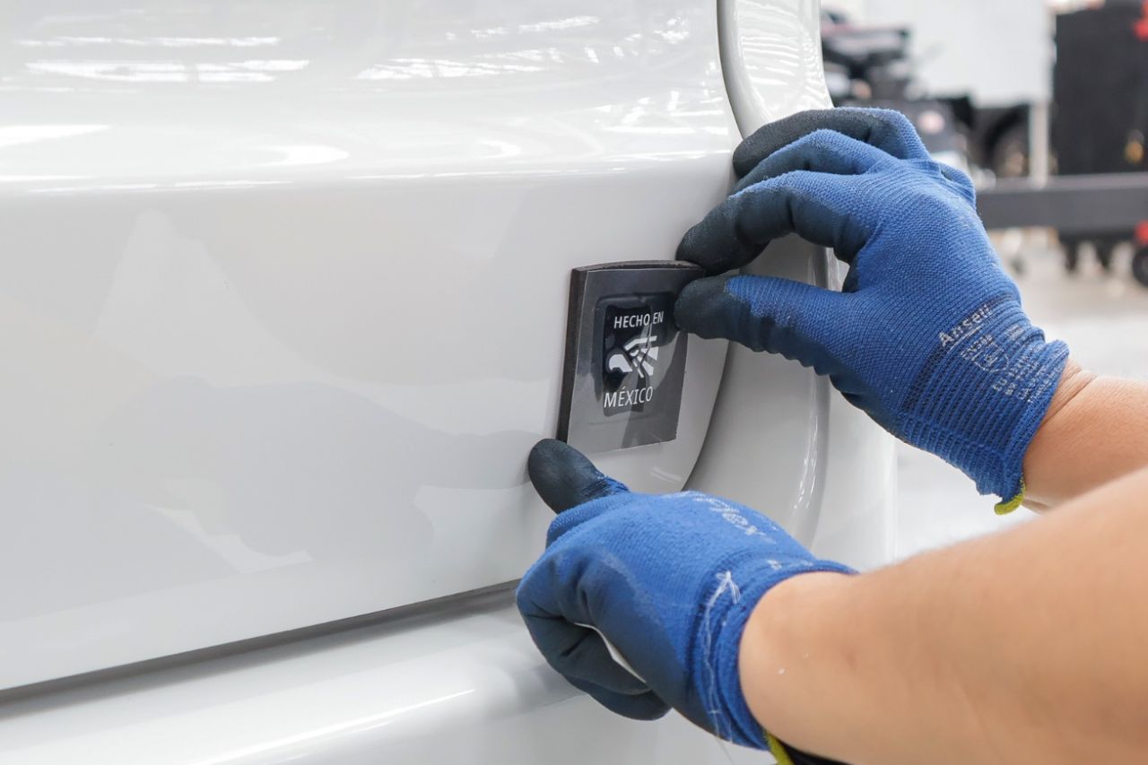Línea de producción de JAC México con trabajadores ensamblando vehículos y poniendo la placa Hecho en México