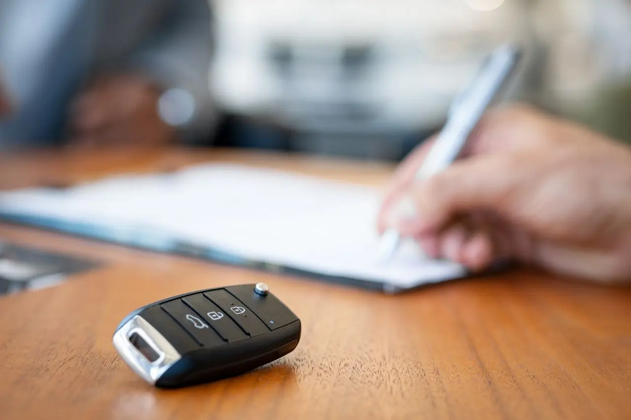 Cliente firma un contrato de crédito automotriz en una agencia de vehículos, reflejando el crecimiento del financiamiento en México.