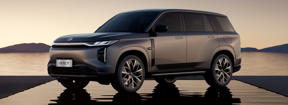 GAC GS7 PHEV 14 Memo Lira Un SUV GS7 gris estacionado sobre una superficie mojada y reflectante al atardecer con el agua y las montañas de fondo que pone de manifiesto su elegante diseño