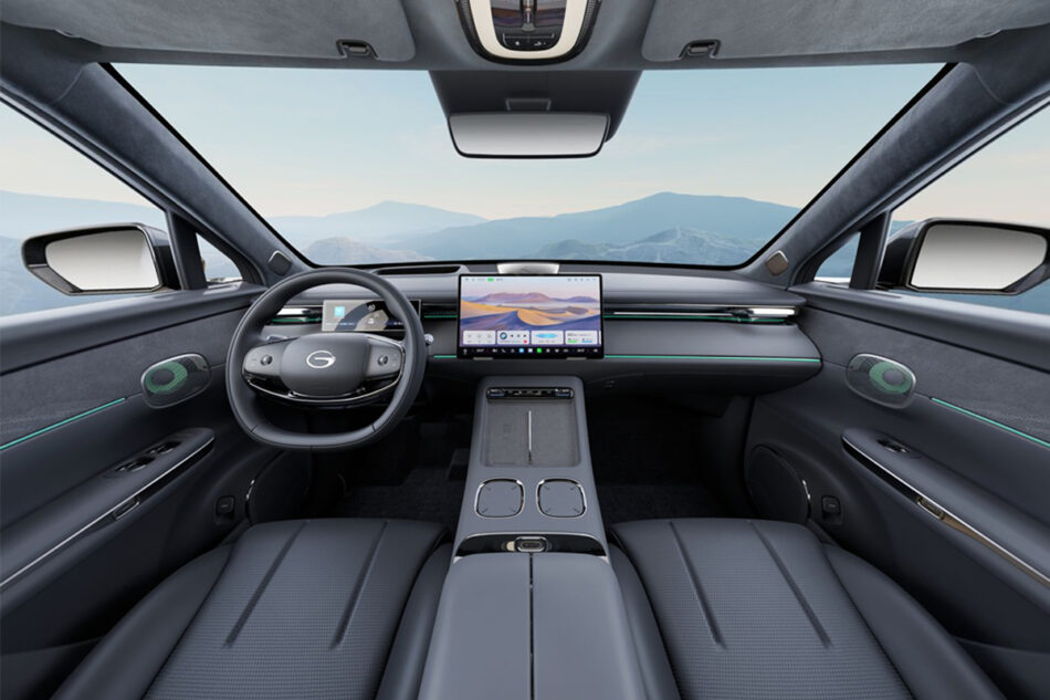 Interiores GAC GS7 PHEV 3 Memo Lira Interior de la cabina de un coche futurista con una gran pantalla táctil central panel de instrumentos digital y paisaje montañoso visible a través del parabrisas