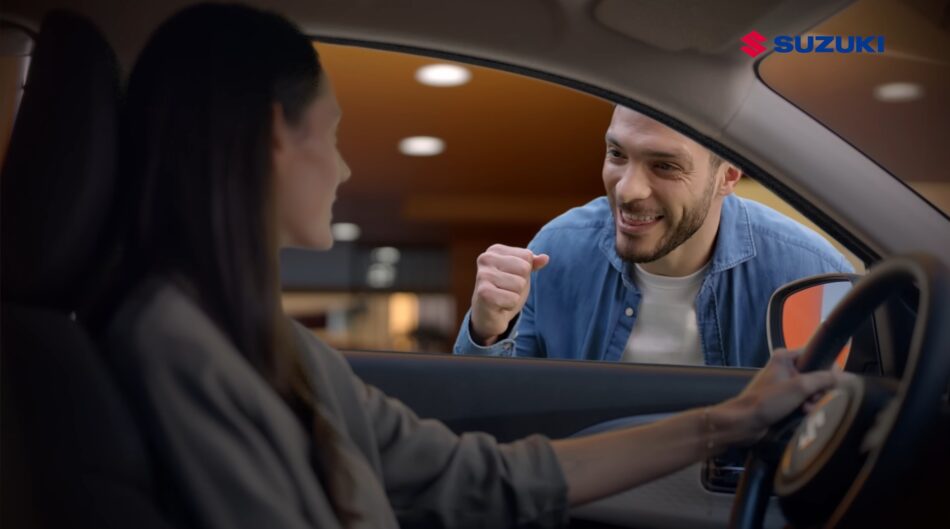 Raúl Jiménez Suzuki 2 Memo Lira Raúl Jiménez saluda a una conductora a través de la ventanilla del coche chocando los puños dentro de una sala de exposición el logotipo de Suzuki en la esquina