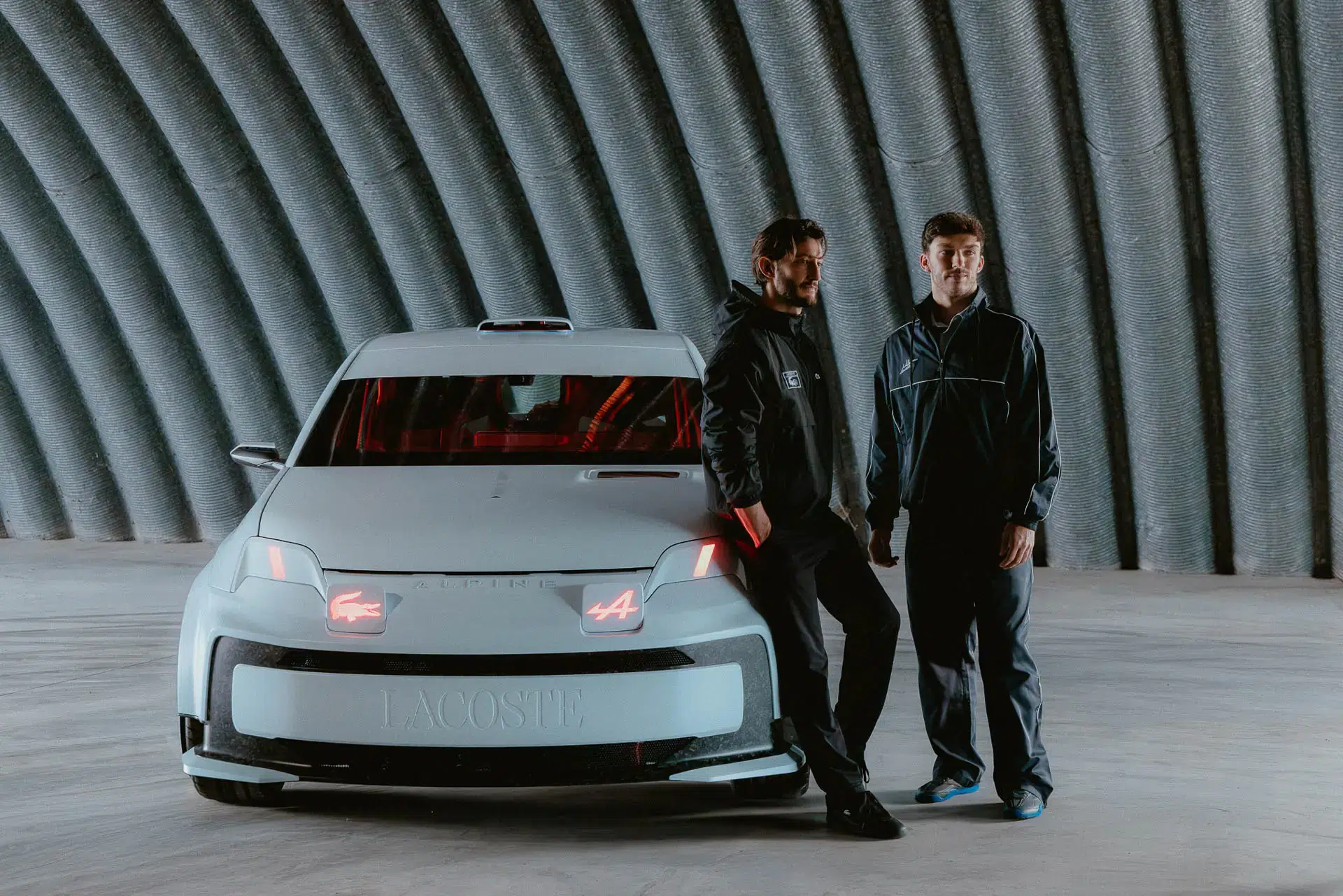 Vista frontal del Alpine Lacoste A290 Rallye con carrocería blanco alpino, detalles en rojo y elementos aerodinámicos de competencia junto a Pierre Niney y Pierre Gasly