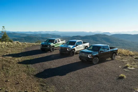 Tres camionetas aparcadas en un mirador rocoso, con una extensa cordillera y un cielo azul al fondo, que muestran un paisaje natural y agreste.