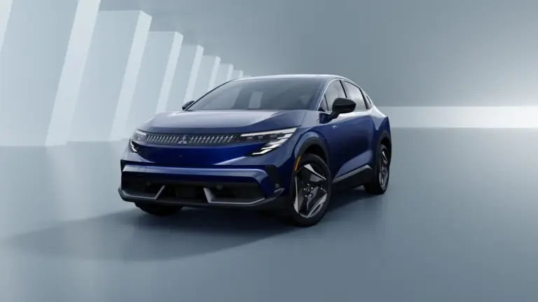 Blue electric SUV shown in a glossy studio setting with abstract white pillar shapes in the background.