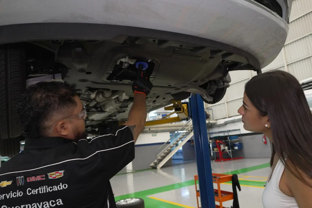 Técnico especializado de General Motors explicando el servicio realizado a un cliente en taller automotriz.