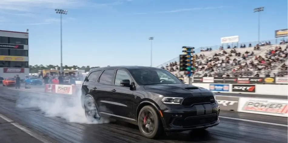 Dodge trae a México la exclusiva Durango SRT Hellcat Black Demon de 710 caballos Memo Lira Black SUV performing a tire burnout on a drag strip as spectators watch from the stands