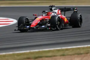 Red Formula 1 race car speeding along a track, sponsor logos visible on the red livery, tires gripping the pavement