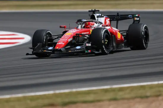 Red Formula 1 race car speeding along a track, sponsor logos visible on the red livery, tires gripping the pavement