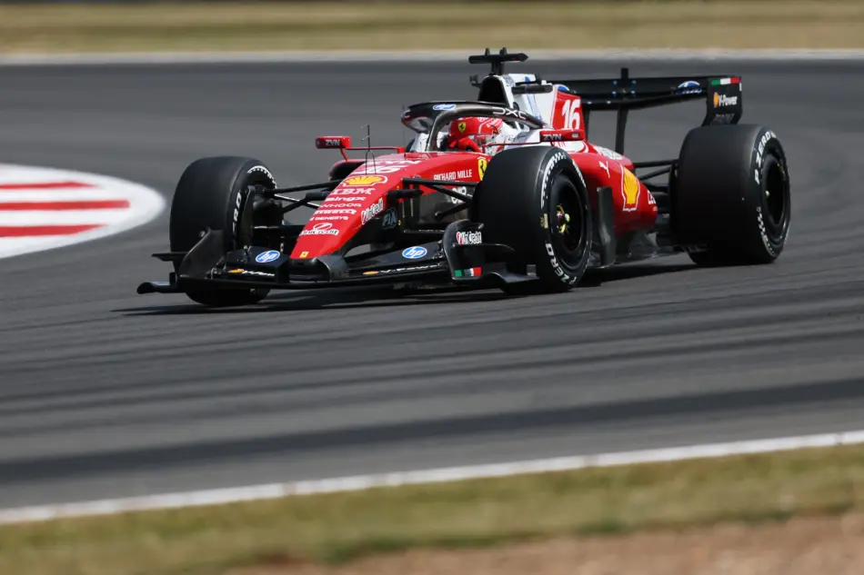 Red Formula 1 race car speeding along a track, sponsor logos visible on the red livery, tires gripping the pavement