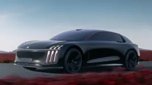Sleek black futuristic car moving along a highway with a clear blue sky and red desert scrub in the background