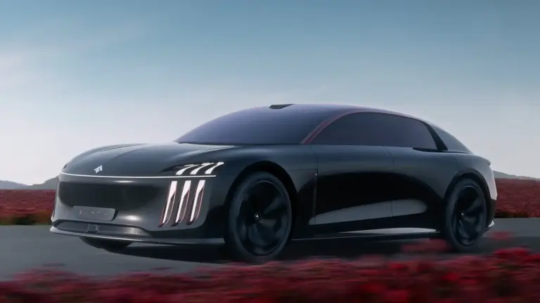 Sleek black futuristic car moving along a highway with a clear blue sky and red desert scrub in the background