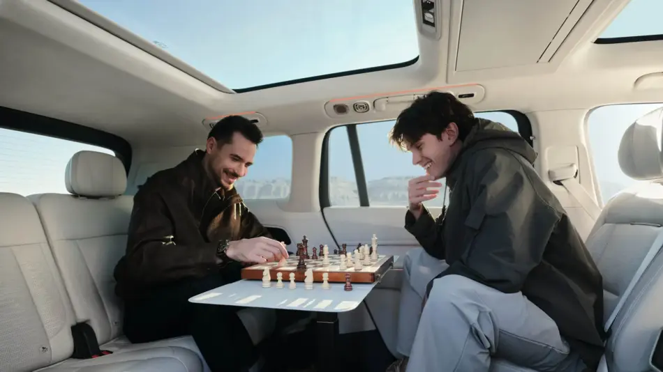 Lynk Co 900 el nuevo rostro del lujo automotriz Memo Lira Dos hombres en el interior del Link Co 900 juegan al ajedrez en un tablero plegable con el techo solar abierto y las montañas a la vista ambos sonrientes